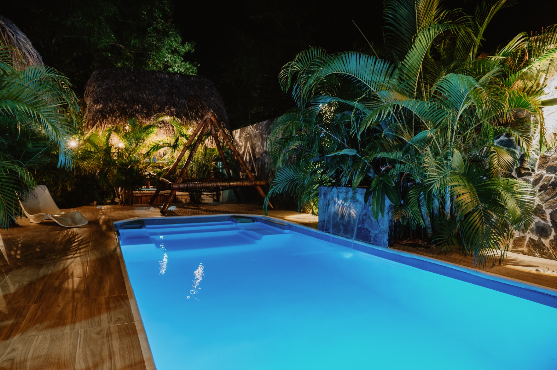 Piscina iluminada de noche entre palmeras